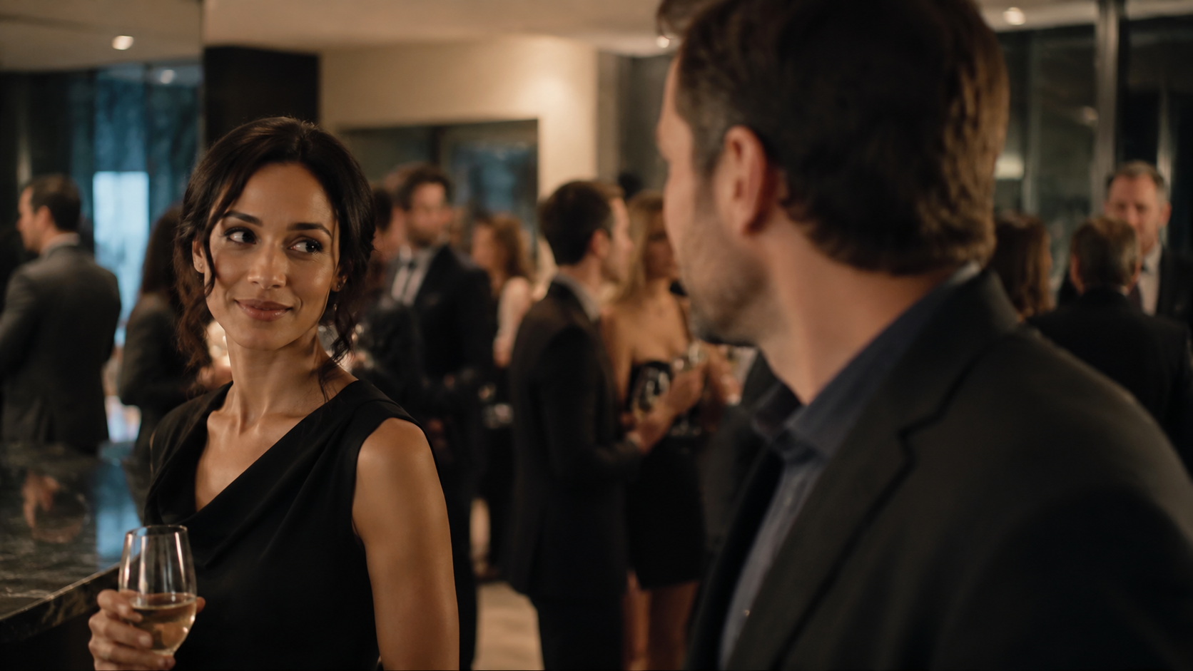 A woman and man exchange an attentive glance across a social gathering